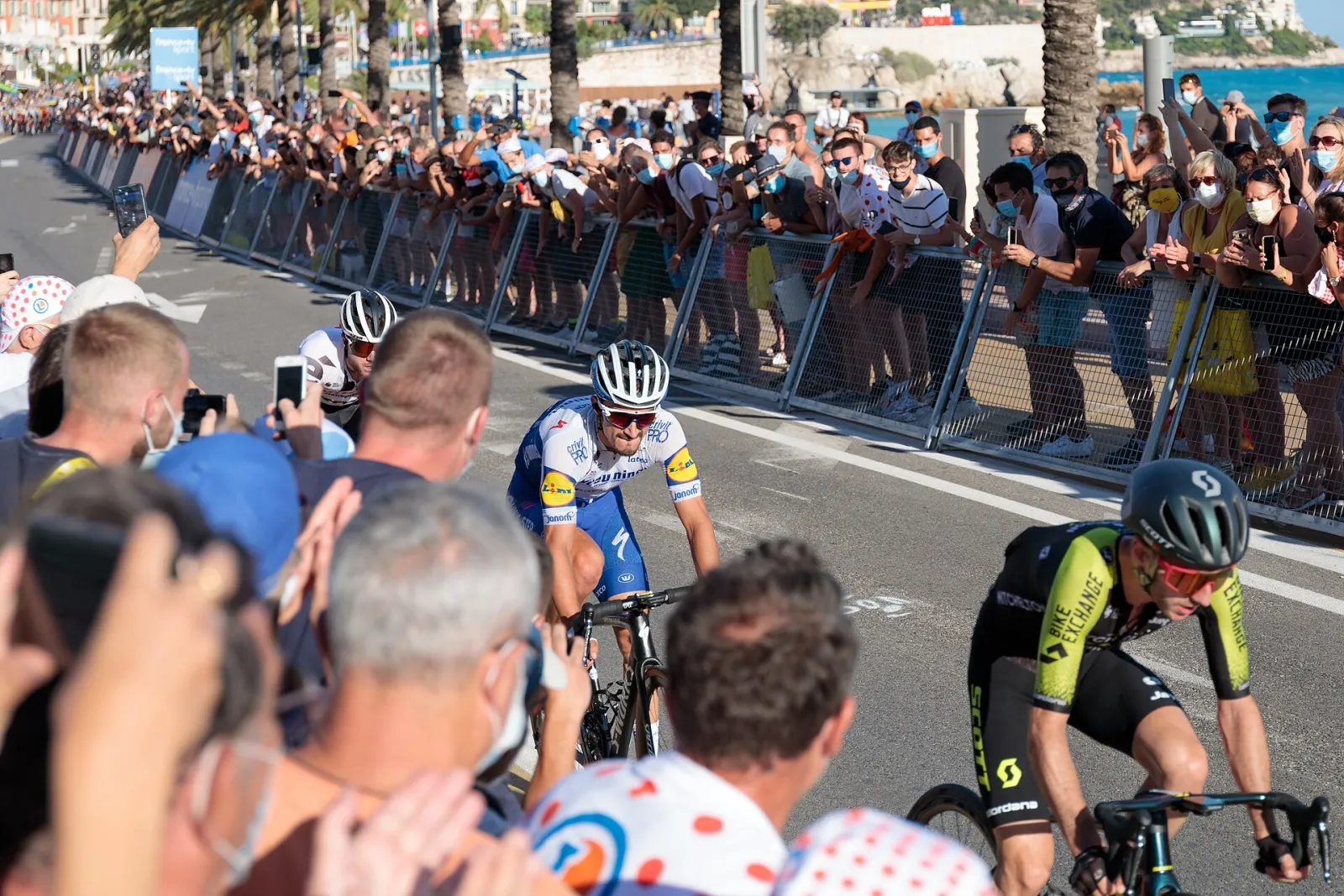 Coureurs du Tour de France 2020 sur le front de mer de Nice, entre deux haies de spectateurs derrière des barrières